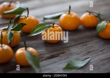 Mandarin-Orange mit Blättern auf Holztisch, selektiver Fokus, sanfte Beleuchtung Stockfoto