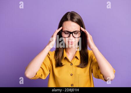 Foto von jungen gestressten Dame Hände halten Kopf Augen geschlossen Tragen Sie Brille gelb Hemd isoliert violette Farbe Hintergrund Stockfoto