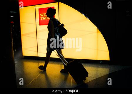 Reisende kommen an einem Wells Fargo-Logo in Penn Station, New York City, USA vorbei. Stockfoto