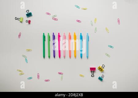 Regenbogenstifte und Büroklammern auf weißem Hintergrund Stockfoto