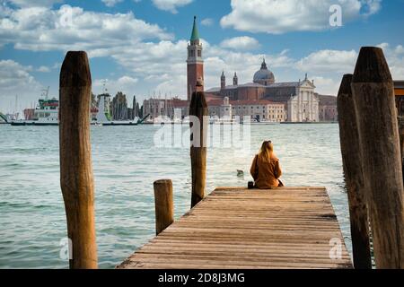 Urlaub in Venedig. Rückansicht eines schönen Mädchens mit Blick auf die Lagune von Venedig mit der Insel San Giorgio Maggiore und Gondeln Stockfoto