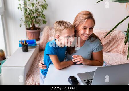 Mutter mit Kind kommuniziert online mit Verwandten über Videokonferenzen auf dem Laptop von zu Hause aus während der Quarantäne. Fernkommunikationskonzept durin Stockfoto
