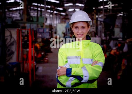 Porträt einer Ingenieurin, die mit Sicherheit gegen die Maschinenumgebung steht Im Werk Stockfoto