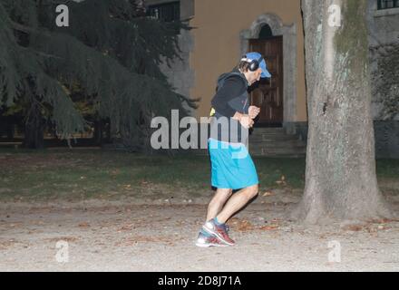 Mailand, Italien, 5. Oktober 2018: Ein sportlicher Mann mit Kopfhörern hört Musik und joggt in einem dunklen Herbstpark spät in der Nacht Stockfoto