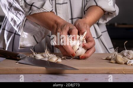 Nahaufnahme der Frau Hände mit orange Nagellack Peeling und Vorbereitung viele Knoblauchzwiebeln. Stockfoto