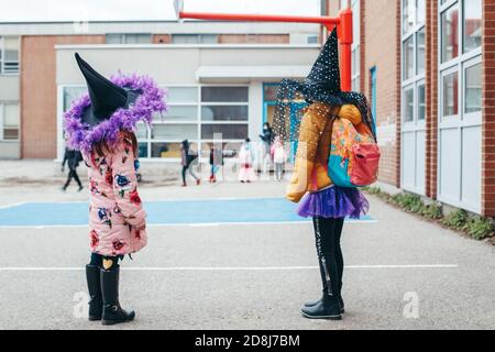 Frohe Halloween. Kinder Mädchen Freunde in Kostümen und Gesicht Schutzmasken gehen zur Schule. Menschen Schüler feiern Halloween-Urlaub. Stockfoto