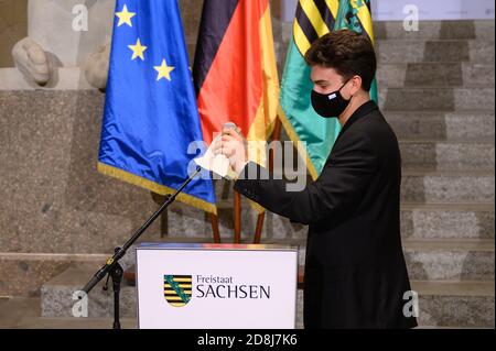 Dresden, Deutschland. Oktober 2020. Ein Mitarbeiter der Sächsischen Staatskanzlei desinfiziert ein Mikrofon, bevor eine Pressekonferenz beginnt. Bundes- und Landesregierungen haben eine teilweise Sperrung ab kommenden Montag beschlossen. Quelle: Sebastian Kahnert/dpa-Zentralbild/dpa/Alamy Live News Stockfoto