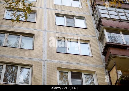 Plastikfenster eines neunstöckigen Paneelhauses, schließen. Holzbalkon Stockfoto