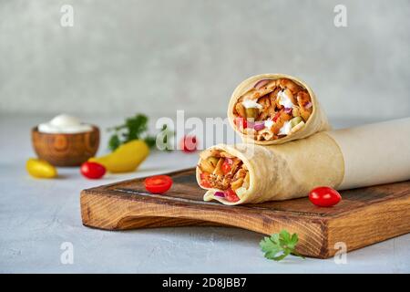 Shawarma mit Huhn und Knoblauchsauce auf Holzbrett. Nahaufnahme Stockfoto