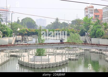 Garten am Fluss mit schwimmenden Bäumen und mehreren Gebäuden Dahinter Stockfoto