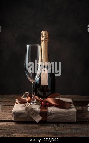 Frohes neues Jahr und frohe Weihnachten, Champagner, Weinglas und Geschenkbox auf braunem Hintergrund. Stockfoto