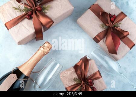 Festlicher Hintergrund mit Geschenken, einer Flasche Champagner und Weingläsern auf einem betongrauen Hintergrund. Stockfoto