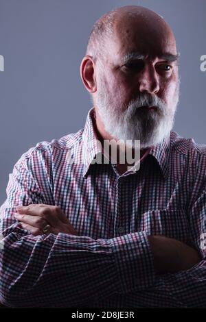 Kahler, bärtiger älterer Mann mit gefalteten Armen. Stockfoto