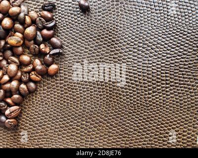 Kaffeebohnen in Nahaufnahme auf einer Lederoberfläche. Draufsicht geröstete Kaffeebohnen auf braunem Leder. Stockfoto