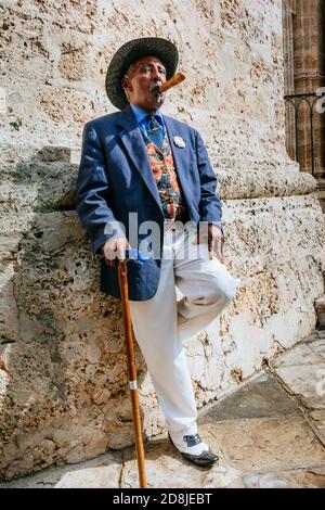 Ein makellos gekleideter kubanischer Herr, der auf den Straßen von Havanna Zigarre raucht. La Habana - La Havanna, Kuba, Lateinamerika und die Karibik Stockfoto