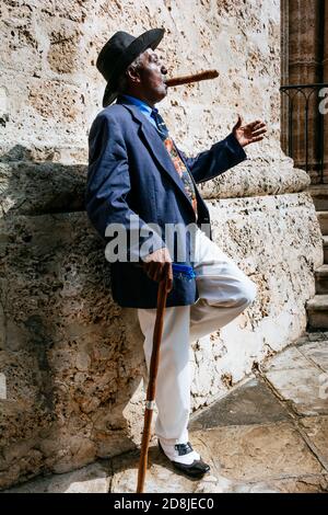 Ein makellos gekleideter kubanischer Herr, der auf den Straßen von Havanna Zigarre raucht. La Habana - La Havanna, Kuba, Lateinamerika und die Karibik Stockfoto