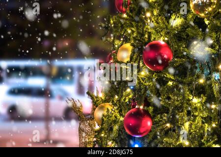 Weihnachtsbaum mit Lichtern in der Stadt glühen, Schnee fallen. Stockfoto