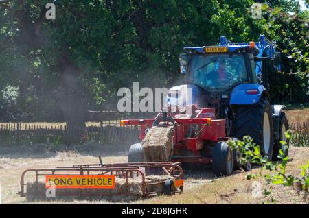 Landwirt im Sommer mit Traktor und Anhänger Heu auf dem Feld in West Wittering, Nr.Chichester, West Sussex, England, Großbritannien Stockfoto