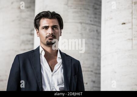 Porträt des jungen Mannes mit trendigen Stil. Trendige Haare und Spitzbart. Er trägt ein weißes Hemd und eine Jacke. Stockfoto