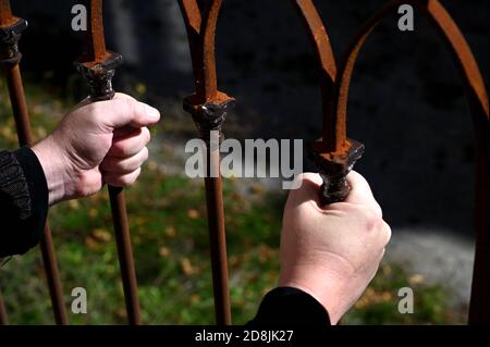 Zwei Hände mit Stahlstangen an einem Zaun Stockfoto