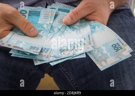 Ein Mann, der ein Bündel von hohem Wert in der Hand hält Brasilianisches Geld Stockfoto