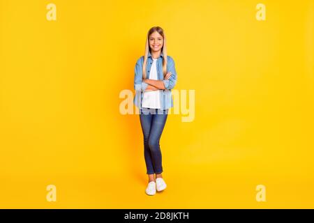 In voller Länge Körpergröße Foto von Schulmädchen mit geraden Blondine Haare halten Hände gekreuzt isoliert auf hellgelben Hintergrund Stockfoto