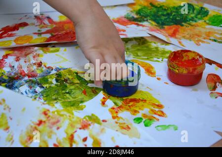 Ein Kind zeichnet. Ein Kind zeichnet Tinten, Fingerfarben, Handdrucke mit dem Finger auf weißem Papier Stockfoto