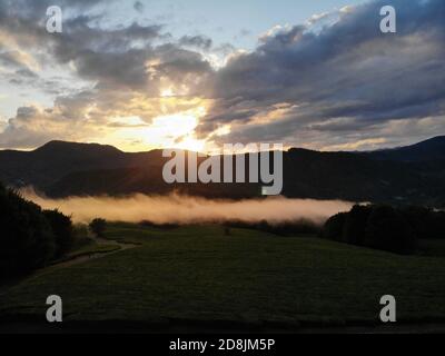 Atemberaubende epische Drohnenaufnahmen. Nebelwolken schweben über Teeplantagen vor dem Hintergrund eines herrlichen Sonnenuntergangs. Stockfoto