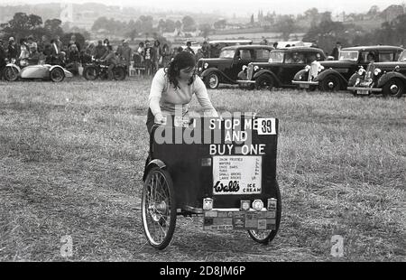 1970er Jahre, historisch, bei einer Transport- und Dampfrallye, draußen auf einem Feld mit einigen Oldtimern auf dem Display, eine junge Frau auf einem traditionellen "Eis"-Dreirad, England, Großbritannien. Stockfoto