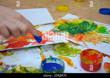 Ein Kind zeichnet. Ein Kind zeichnet Tinten, Fingerfarben, Handdrucke mit dem Finger auf weißem Papier Stockfoto