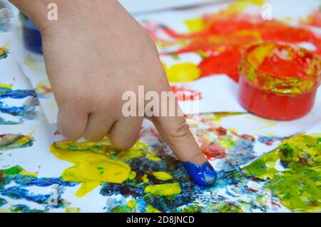 Ein Kind zeichnet. Ein Kind zeichnet Tinten, Fingerfarben, Handdrucke mit dem Finger auf weißem Papier Stockfoto