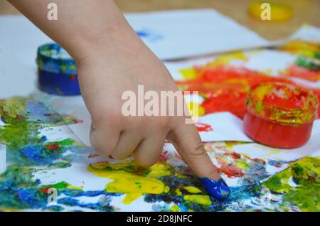 Ein Kind zeichnet. Ein Kind zeichnet Tinten, Fingerfarben, Handdrucke mit dem Finger auf weißem Papier Stockfoto