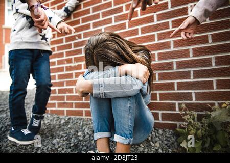 Traurige Einschüchterung Moment. Mädchen sitzen auf dem Boden Mobbing in Schulhof Stockfoto