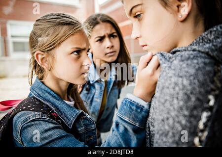 Ein trauriges Mädchen Einschüchterung Moment auf der elementaren Alter Mobbing Auf dem Schulhof Stockfoto