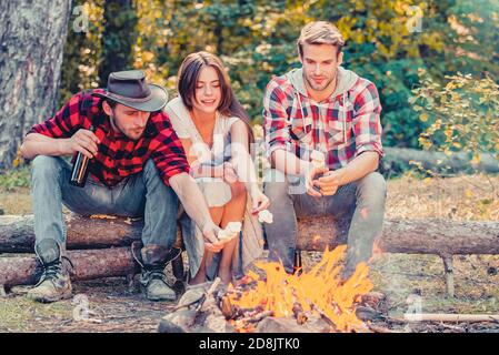 Glückliche junge Freunde beim Picknick. Gruppe von Freunden genießen Picknick im Wald. Glückliche Freunde auf einem Campingausflug am Lagerfeuer entspannen. Unternehmen Stockfoto