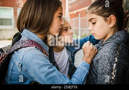 Ein trauriges Mädchen Einschüchterung Moment auf der elementaren Alter Mobbing Auf dem Schulhof Stockfoto