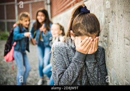 Ein trauriges Mädchen Einschüchterung Moment auf der elementaren Alter Mobbing Auf dem Schulhof Stockfoto