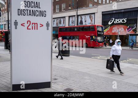 Zwei Meter lange soziale Distanzierungsschilder weisen Käufer der Oxford Street an, sich nach den Richtlinien der Regierung während der zweiten Welle der britischen Coronavirus-Pandemie am 30. Oktober 2020 in London, England, auseinander zu halten. Stockfoto