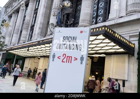 Zwei Meter lange soziale Distanzierungsschilder weisen Käufer der Oxford Street an, sich außerhalb von Selfridges zu halten, gemäß den Richtlinien der Regierung während der zweiten Welle der britischen Coronavirus-Pandemie am 30. Oktober 2020 in London, England. Stockfoto