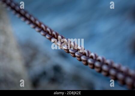 Eine Kette kreuzt das Bild von oben links nach unten rechts. Im Hintergrund ist verschwommen und blau. Stockfoto