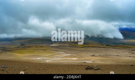 Kurvenreiche Straße durch das Tal des Vulkans Cotopaxi und niedrige Wolken in der Ferne, Cotopaxi, Ecuador Stockfoto