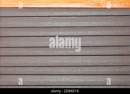 Braune Vinylgleitung mit Holzimitat Maserung. Vinyl-Struktur und Siding Hintergrund in Außenwand Oberfläche. Stockfoto