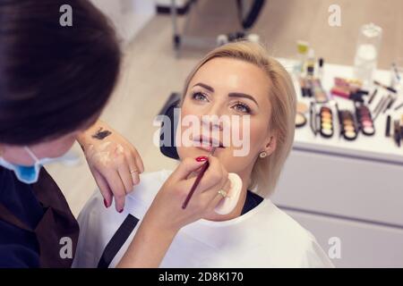 Reife Frau mit Make-up Lipgloss auf den Lippen in einem aufgetragen Schönheitssalon im Hintergrund Stockfoto