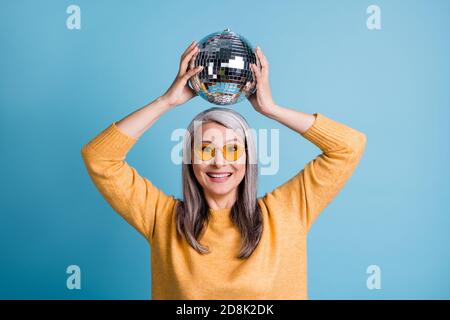 Nahaufnahme Foto von charmanten hübschen alten Dame Hände halten Silver Disco Ball über Kopf treffen Unternehmen Spaß haben hören club Musik Tanz tragen Sonnenglas Stockfoto