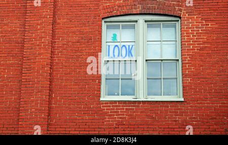 Ein Fenster in einem Backsteingebäude mit einem Sichtschild. Stockfoto