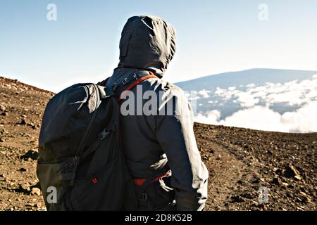 Ein Wandertourist, der einen atemberaubenden Blick auf den Mauna Kea Vulkan auf der Big Island von Hawaii genießt. Stockfoto