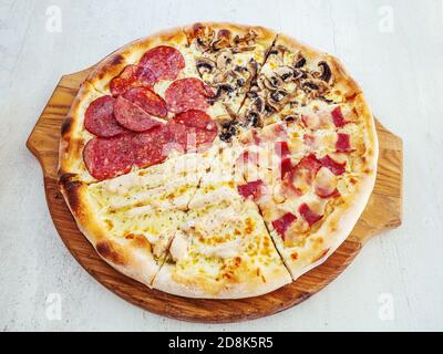 Assotri Pizza mit Wurst, Pilzen, Speck und Hühnerfleisch liegt auf einem Holztablett Stockfoto