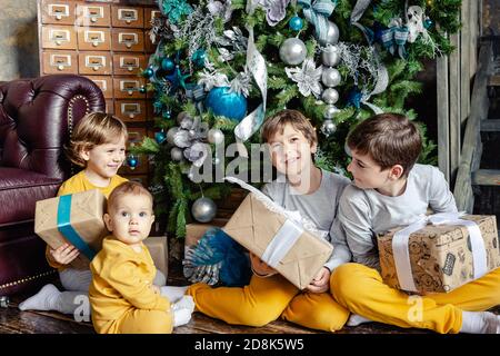 Glückliche Kinder Brüder Eröffnung Geschenke vor Weihnachtsbaum. Weihnachtszeit. Konzentrieren Sie sich auf das Baby. Stockfoto