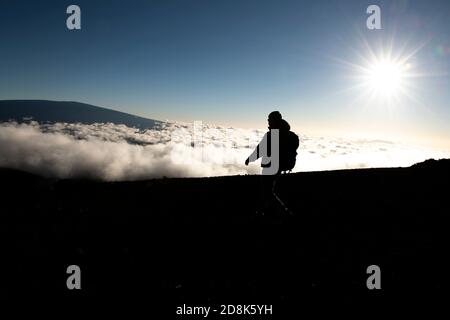 Ein Wandertourist, der einen atemberaubenden Blick auf den Mauna Kea Vulkan auf der Big Island von Hawaii genießt. Stockfoto