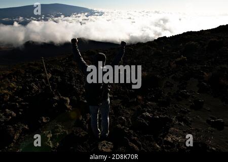 Ein Wandertourist, der einen atemberaubenden Blick auf den Mauna Kea Vulkan auf der Big Island von Hawaii genießt. Stockfoto